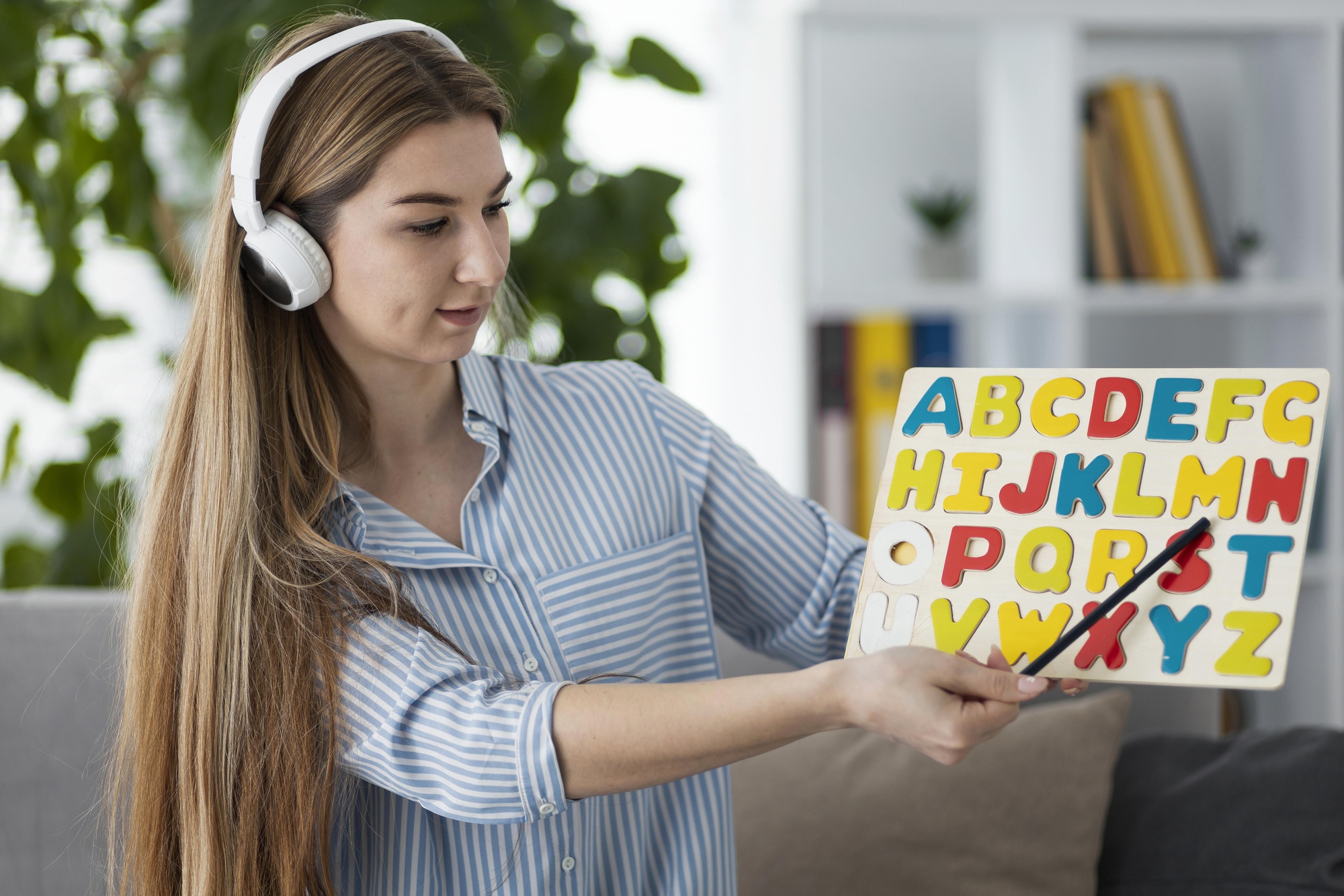 chica con cascos sujetando un carte con las letras del abecedario